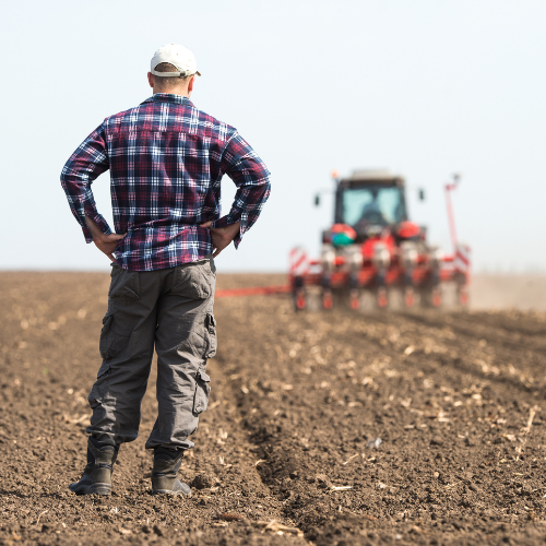 Rural scene with a farmer in the foreground and a tractor in the field